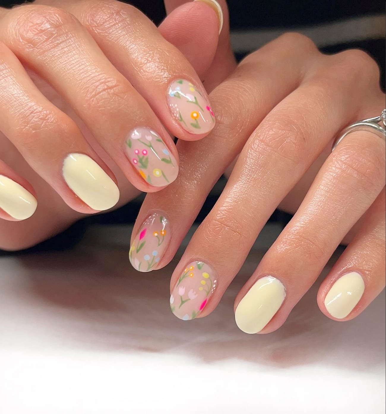 Solid yellow nails with colorful floral designs
